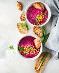 Beetroot cream soup with coconut milk, baked chickpeas, sesame, parsley on a gray concrete background. Baked chickpeas with spices. Useful dietary snack and lunch. Place for text. Flat lay, top view