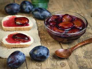 Bowl with plum jam and bread smeared with jam.