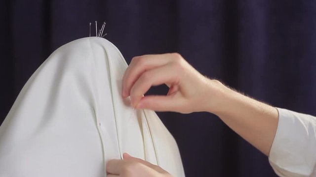 A woman designer wears beside a dummy and makes clothes with a dummy method. Drapery of fabric folds on the mannequin