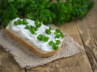 A piece of wheat bread smeared with fresh curd cream on a piece of burlap.