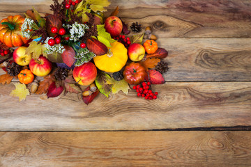 Fall rustic background with red berries, white flowers, yellow squash, apples, cones, acorns,...