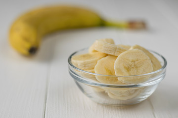 Chopped pieces of banana in a glass bowl on a wooden table.