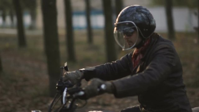 Man Riding old custom cafe-racer Motorcycle on Country Road at sunset 