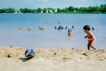 Little latin siblings having a good time in the beach of a lake.