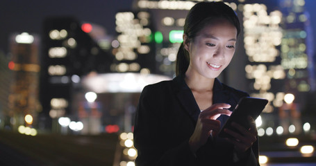 Businesswoman working on mobile phone in city at night