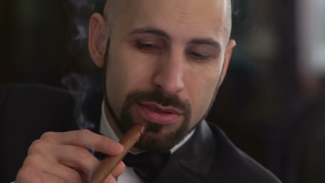 Elegant man in a suit smoking a cigar, slow motion.