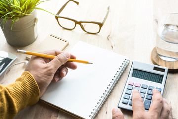 Male working with calculator and notepad on worktable.business plan,financial,lifestyle concepts...
