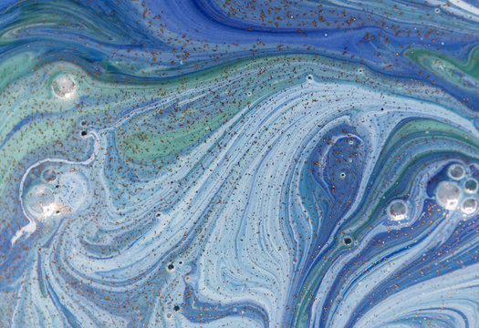 Marbled green and blue abstract background with golden sequins. Liquid marble ink pattern.