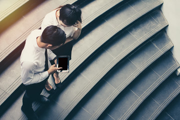 businessman and woman using tablet of working. Meetings the commercial activities in promoting. Together create a mutually beneficial on stairs.outside