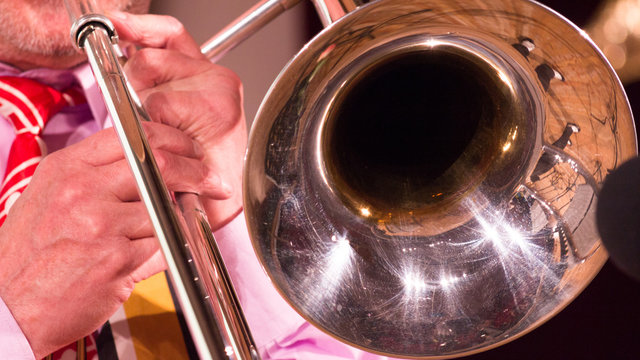 In the hands of a musician a trombone while playing jazz. close-up