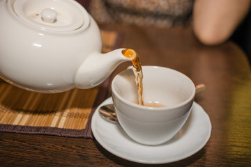 Obraz premium Pour tea from a teapot into a mug