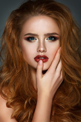 Beautiful woman portrait with gorgeous red hair and with hand touching lips.