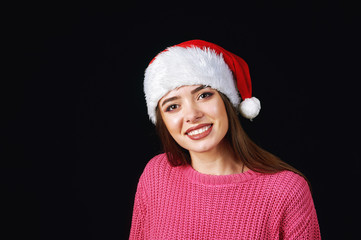 Young woman in Santa hat on a dark background