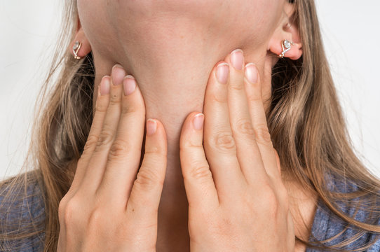 Woman with throat sore is holding her aching throat