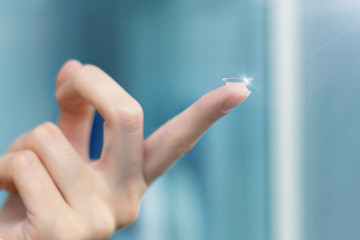 girl holds finger on a contact lens, closeup