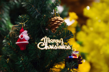 Merry Christmas text sign ornament attached on Xmas tree - selective focus.
