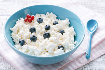 Organic curd cheese, farmer's cheese or cottage cheese in blue bowl. Closeup view. Healthy diet, dairy products concept
