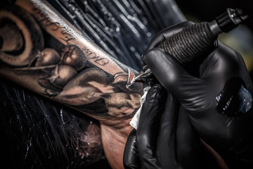 Artist tattooing of man's skin