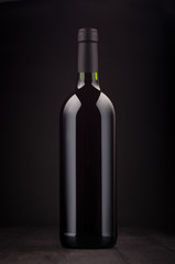 Bottle of red wine mock up on elegant dark black wooden background, vertical.