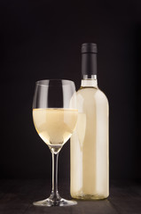 Bottle of white wine and wine glass mock up on elegant dark black wooden background, vertical.