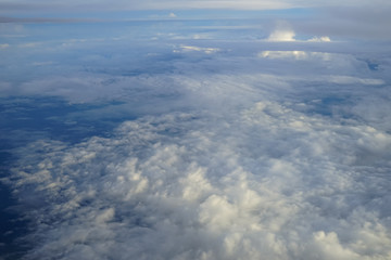 Naklejka na ściany i meble View of beautiful abstract soft white cloudscape with shades of blue sky background from flying plane window
