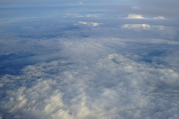 View of beautiful abstract soft white cloud with shades of blue sky background from above flying plane window