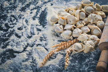 Traditional russian pelmeni, ravioli, dumplings with meat on black concrete background. Top view. Copyspace.