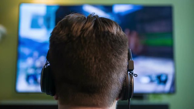 Gamer Guy w/ Headphones. Male plays an FPS videogame while wearing headphones.