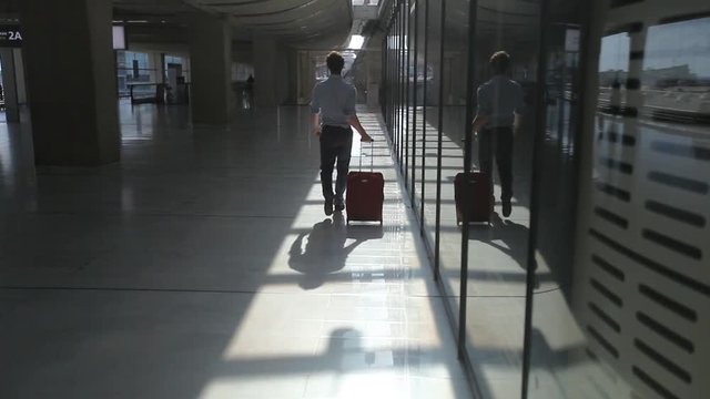 man passenger walking with luggage in the corridor of modern airport