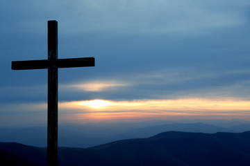 wooden cross on a background of sunrise in the mountains.