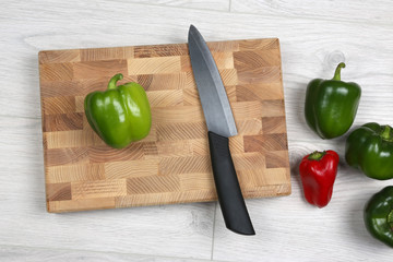 sweet peppers with a ceramic knife on a wooden board