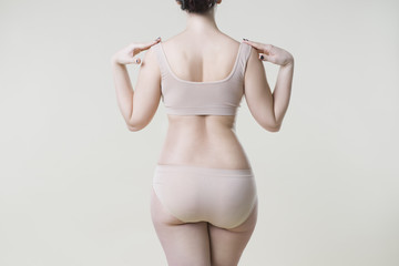 Woman in beige underwear on studio background, cellulite on female body