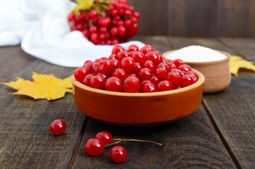 Red viburnum in a ceramic bowl, sugar, a bunch of berries for tea, jam.