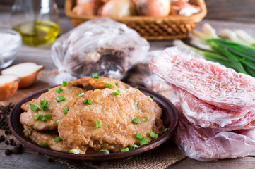 Pork schnitzel in a plate and frozen pork neck chops meat