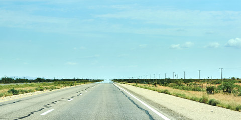Fototapeta premium Long straight road leading to distance with heat making mirage