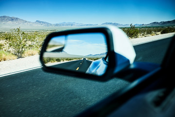 Long straight road in a car side mirror