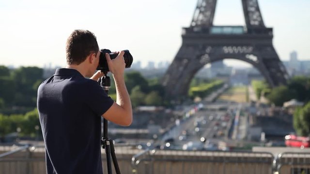 photographer with tripod and professional dslr camera taking photo of Eiffel tower in Paris