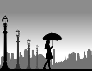 Young woman walking under the umbrella on the street in autumn or fall, one in the series of similar images silhouette