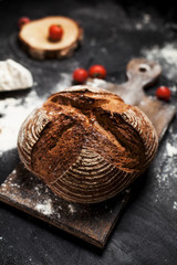 freshly baked bread, flour and tomatoes on a wooden board on a table