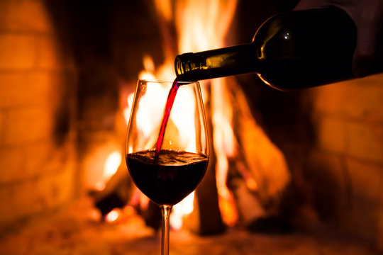 Bottle of wine and a glass against the fire