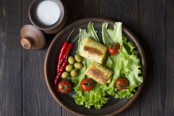 pancakes and fresh organic vegetables: tomatoes, peppers, parsley, lemon, cucumber, chili, spices and olives in a clay plate on the table dark wood