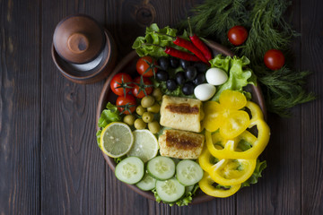 pancakes and fresh organic vegetables: tomatoes, peppers, parsley, lemon, cucumber, chili, spices and olives in a clay plate on the table dark wood