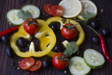 Fresh organic vegetables: tomatoes, pepper, parsley, lemon, cucumber, chili, spices on a dark wooden table