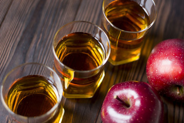 red Apple with Apple juice on a wooden table close up