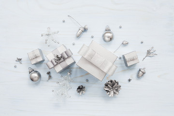 Silver colored composition made of gift boxes and Christmas decorations on light blue wooden background. Top view, New Year and Christmas greeting card concept.