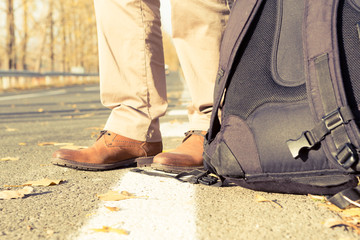 Feet and backpack of a male traveler or hitchhiker