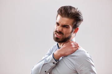 Portrait of young businessman who is having pain in his neck.