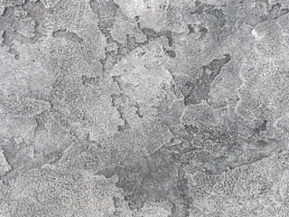 Old gray wall covered with uneven plaster. Texture of vintage shabby silver stone surface, closeup.