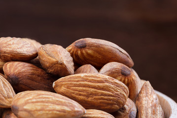 Almonds in bowl on wooden background