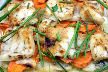 Prepared fried fish with onion, greens, carrot and spices top view closeup